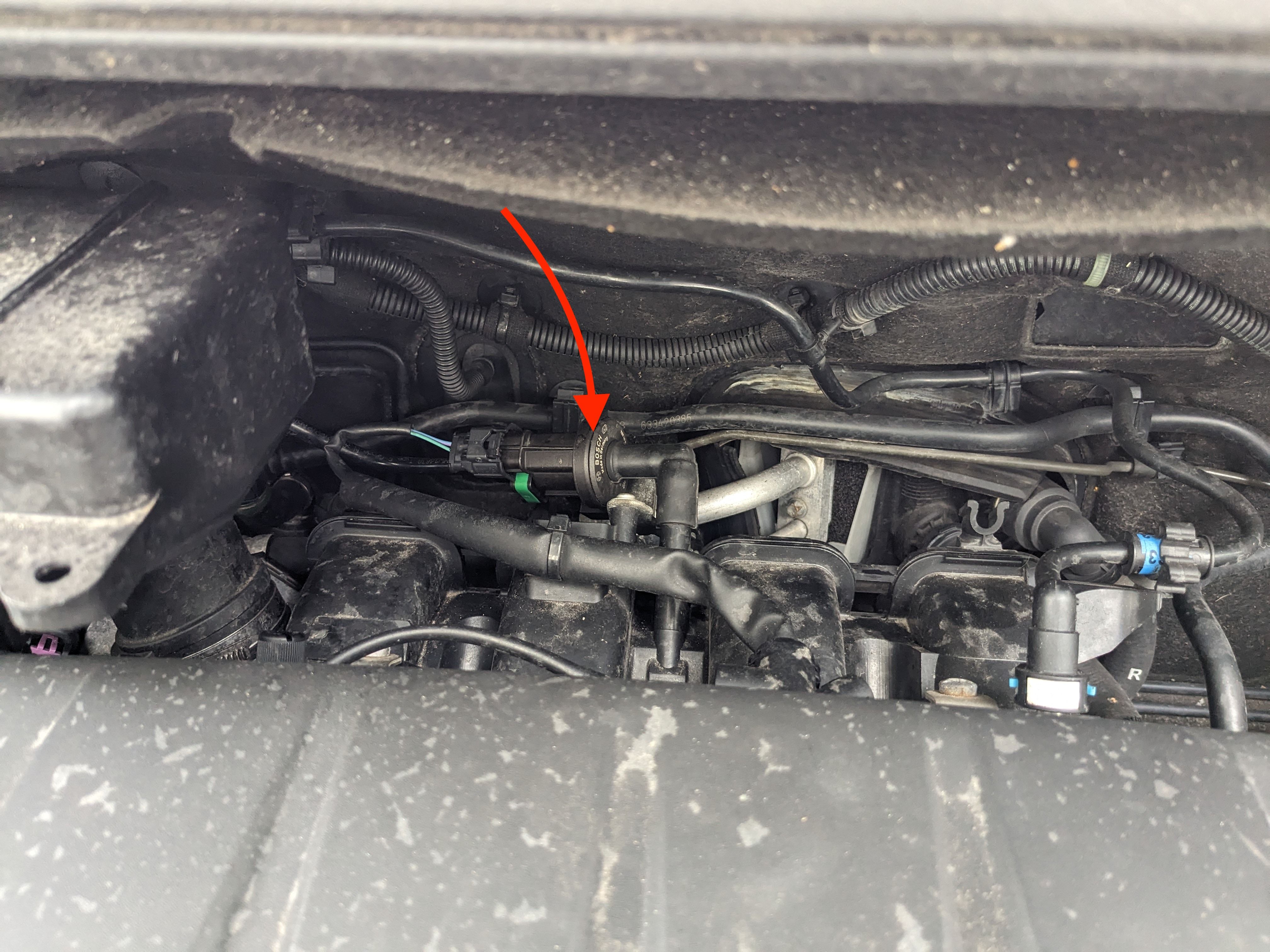 Closer up view of a Vauxhall Corsa engine bay, arrow pointing to the purge valve