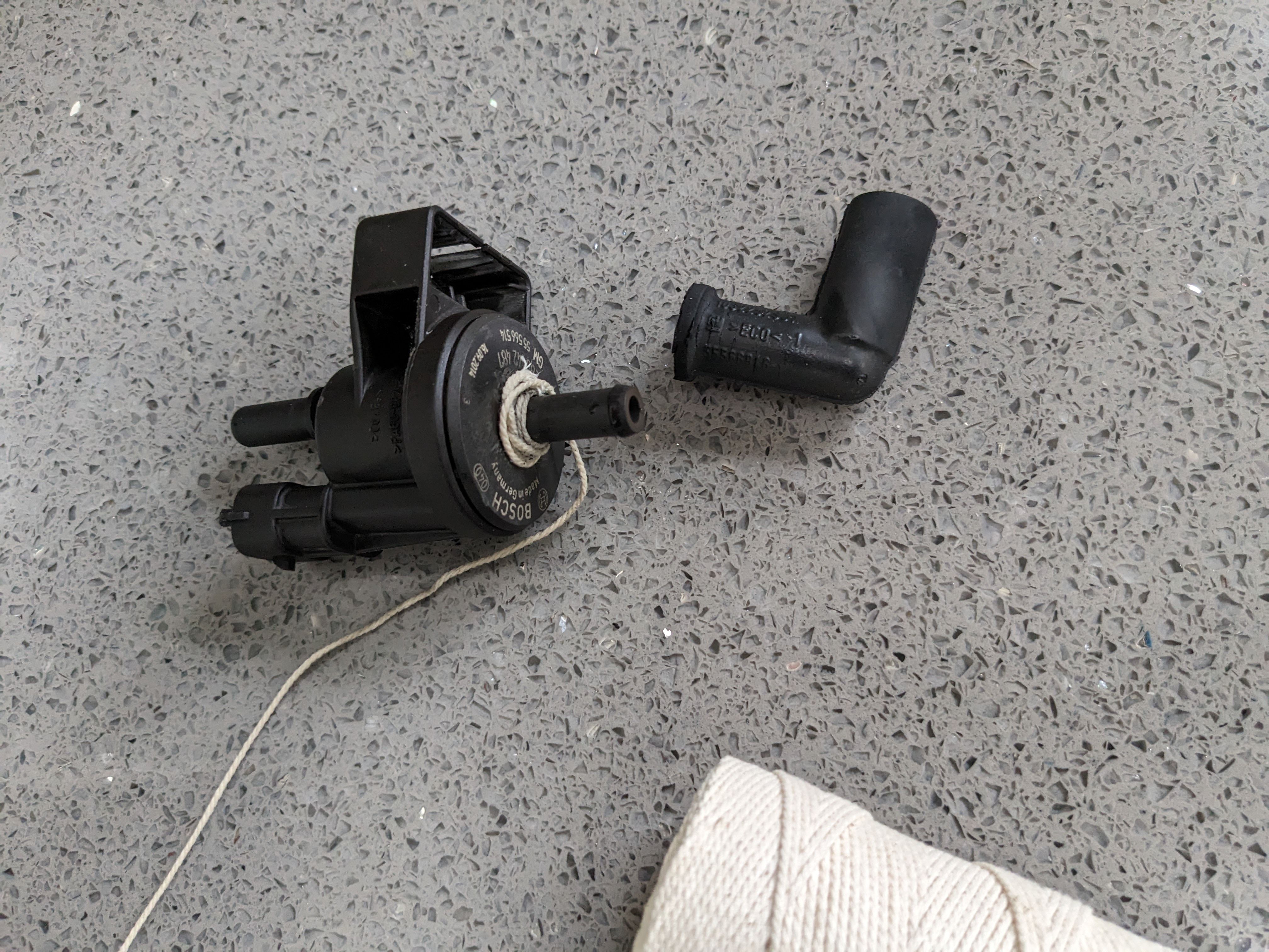 String wrapped around purge valve plastic tube to remove the rubber L shaped hose